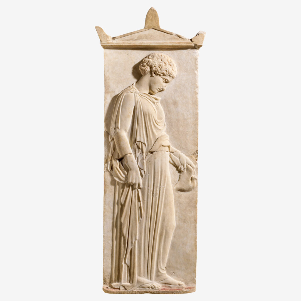 Μαρμάρινη ταφική στήλη με ανάγλυφη παράσταση κοριτσιού ενδεδυμένου με πέπλο. Χαμηλώνει το κεφάλι και με θλιμμένη έκφραση κοιτάζει το περιστέρι που κρατά από τα φτερά στο αριστερό της χέρι.