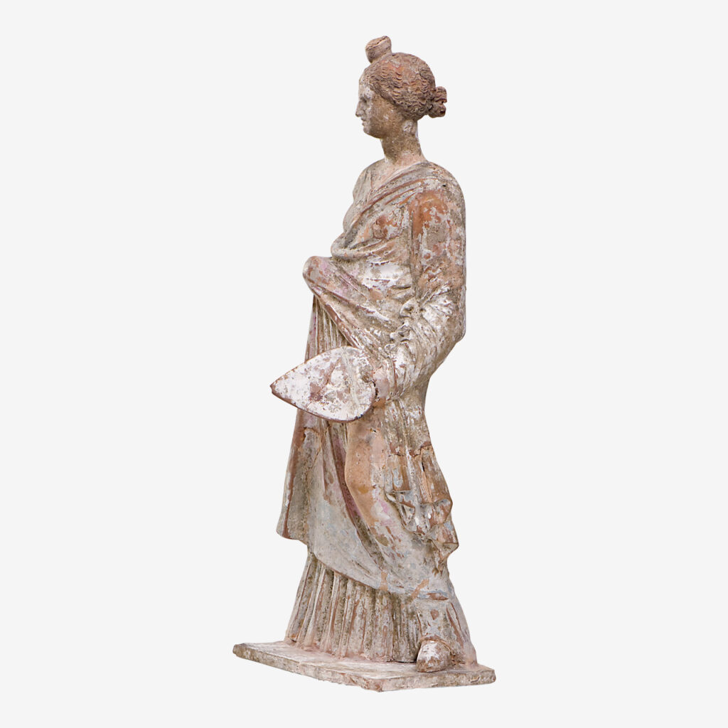 Πήλινο ειδώλιο γυναικείας μορφής του τύπου της Ταναγραίας με καρδιόσχημο ριπίδιο. 